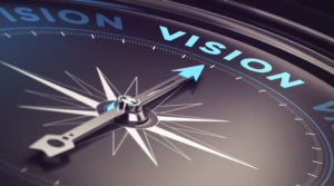 A compass with an arrow pointed to the word vision. Vision is about charting your course.