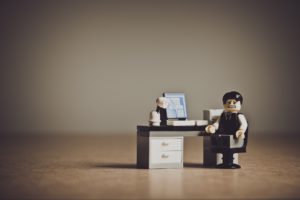 A picture of a Lego man at a Lego desk with a grimace expression. 