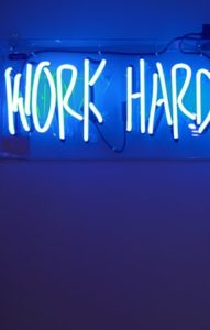 A neon sign that says work hard. Nothing gets accomplished without hard work.